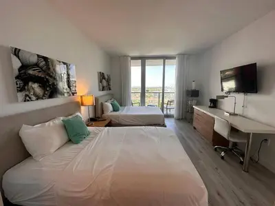 a hotel room with two beds and a desk and a computer at Cozy Miami Studio Perfect for Vacation or Work! in Hallandale Beach