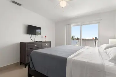 a white bedroom with a bed and a television at Lakeside Retreat with Private Yard & Kayak in Fort Lauderdale