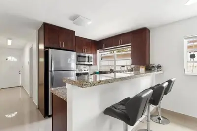 a kitchen with brown cabinets and a counter with chairs at Lakeside Retreat with Private Yard & Kayak in Fort Lauderdale