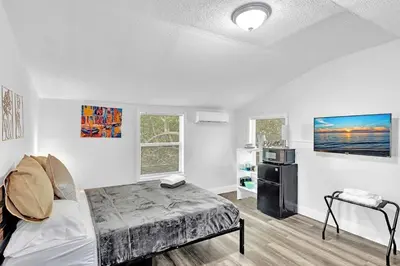 a bedroom with a bed and a refrigerator in it at Boutique Vacation Studio - Beach, Mall, Casino Hn2 in Hallandale Beach