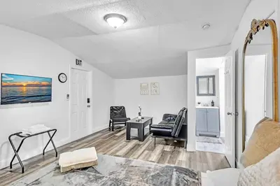 a white living room with a table and a chair at Boutique Vacation Studio - Beach, Mall, Casino Hn2 in Hallandale Beach