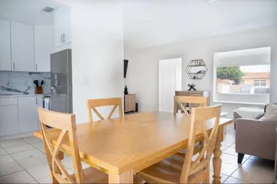 a kitchen and dining room with a wooden table and chairs at Coral Gables Home with POOL Near Airport. King beds in Miami