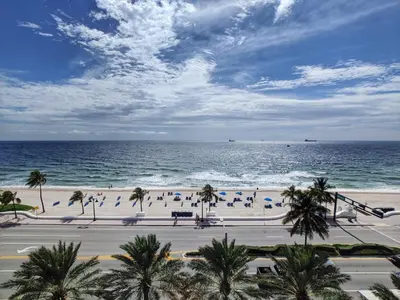 a beach with palm trees and people on the beach at Your Private Oceanfront Sanctuary 2BR 2BA in Fort Lauderdale
