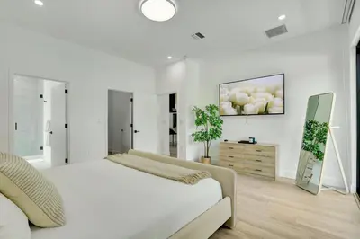 a white bedroom with a bed and a painting on the wall at Radiance - Modern Design, Poolside Escape in Miami
