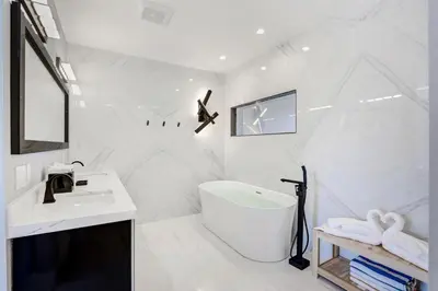 a white bathroom with a tub and a sink at Deco Delight - Central Hub in Miami