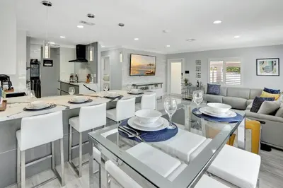 a kitchen and living room with a table and chairs at The Gardens - Luxe, Pool, Mins to Hard Rock Stadium in Miami Gardens