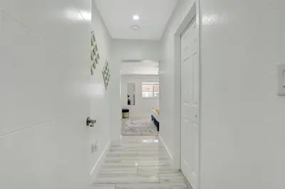 a hallway with white walls and a white door at The Gardens - Luxe, Pool, Mins to Hard Rock Stadium in Miami Gardens