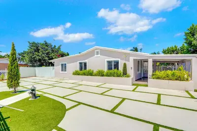 a white house with a garden in front of it at The Gardens - Luxe, Pool, Mins to Hard Rock Stadium in Miami Gardens