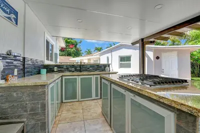 a large outdoor kitchen with a grill and a counter at The Gardens - Luxe, Pool, Mins to Hard Rock Stadium in Miami Gardens
