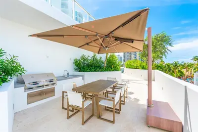 a patio with a table and a grill and an umbrella at Tiffany Hazel - Rooftop Pool, Gym, & Walk to Beach in Fort Lauderdale