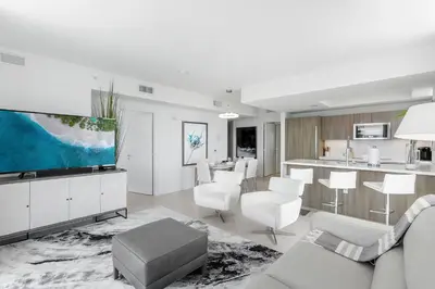 a living room with white furniture and a kitchen at Tiffany Hazel - Rooftop Pool, Gym, & Walk to Beach in Fort Lauderdale
