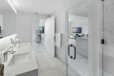 a white bathroom with a shower and a sink at Tiffany Ebony - Ocean & Canal views, Walk to Beach in Fort Lauderdale