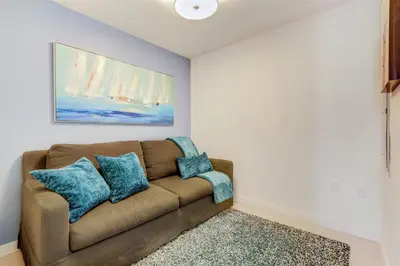 a living room with a brown couch with blue pillows at Tiffany Coral - 6th FL, Pool, Gym, & Mins to Beach in Fort Lauderdale