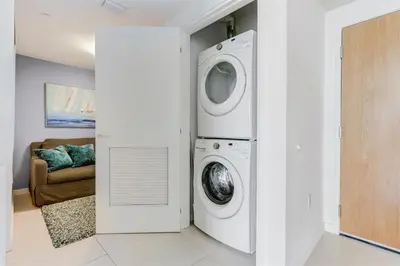 a washer and dryer in a living room with a couch at Tiffany Coral - 6th FL, Pool, Gym, & Mins to Beach in Fort Lauderdale