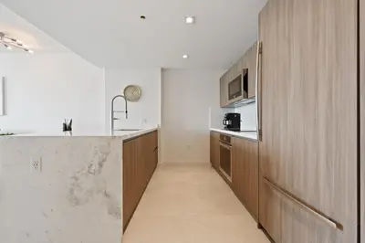 a kitchen with wooden cabinets and a counter top at Tiffany Sage - Rooftop Pool, Gym, & Walk to Beach in Fort Lauderdale