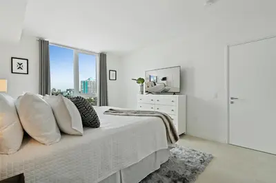 a white bedroom with a bed and a window at Tiffany Sage - Rooftop Pool, Gym, & Walk to Beach in Fort Lauderdale