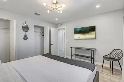 a white bedroom with a bed and a chair at Renovated professional design, grill lake view! 1 in Hallandale Beach