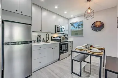 a kitchen with white cabinets and a stainless steel refrigerator at Renovated professional design, grill lake view! 1 in Hallandale Beach