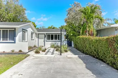 a white house with a hedge in front of it at Renovated professional design, grill lake view! 1 in Hallandale Beach