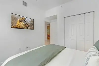 a white bedroom with a tv hanging on the wall at Artease 2 -Largest, stylish, Peloton bike, near Wynwood Walls & restaurants in Miami