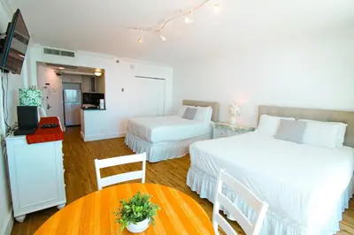a bedroom with two beds and a table with a television at Castle 1029 Balcony studio with Ocean View, Pool, Tennis and Free Parking in Miami Beach