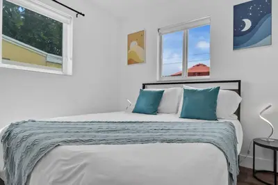 a white bedroom with a large bed with blue pillows at Escape to Private Poolside Bliss in Hollywood