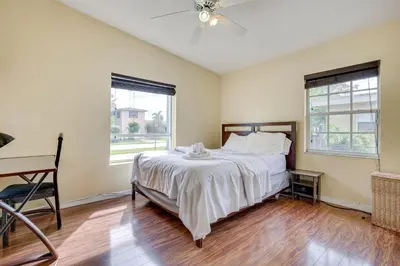 a bedroom with a bed and a desk and two windows at 4 Mi to Beach Hollywood Home with Patios! in Hollywood