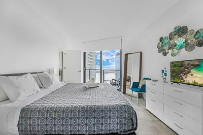a white bedroom with a bed and a tv at Exclusive High-Rise Edgewater 1BD - Tennis & Sauna in Miami