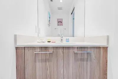 a bathroom with a white sink and wooden cabinets at Exclusive High-Rise Edgewater 1BD - Tennis & Sauna in Miami