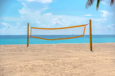 a volleyball net on a beach with the ocean at Quiet Oasis Steps From Shops with Golf View-CS61 in Hollywood
