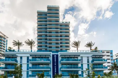 a tall building with palm trees in front of it at Ocean 2 Sky at Monte Carlo Miami Beach in Miami Beach