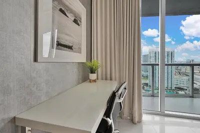 a white desk with two chairs in a room with windows at Perfect One Bedroom at Icon Brickell Amazing views in Miami