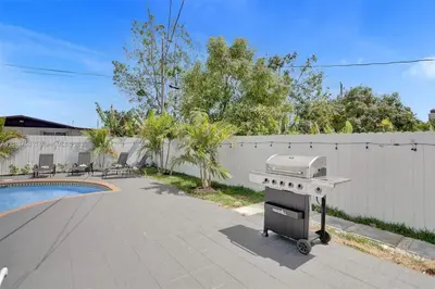 a barbecue grill on a sidewalk next to a fence at Cozy Fun House 4 2 Aventura Stadium Beach in North Miami Beach