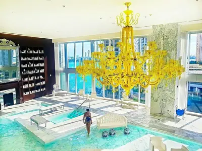 a woman standing in a swimming pool with a large chandelier at Stylish Studio Icon, W Hotel Waterfront Building in Miami