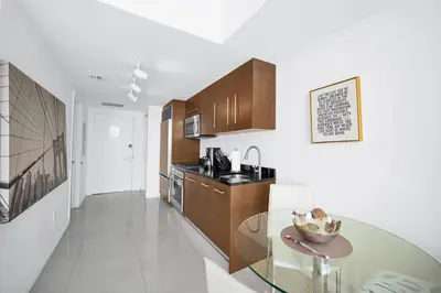 a kitchen with wooden cabinets and a glass table at Stylish Studio Icon, W Hotel Waterfront Building in Miami