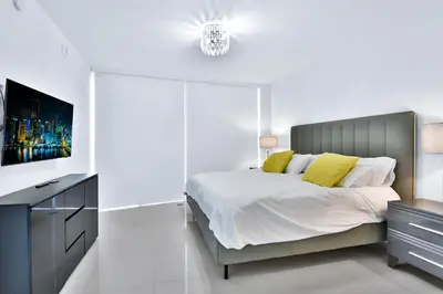 a white bedroom with a bed and a tv at Amazing 2 Bedroom at Icon in the Heart of Brickell in Miami