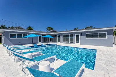 a swimming pool with chairs and a house at Sunshine Manors 2009 B in Fort Lauderdale