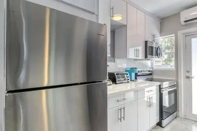 a stainless steel refrigerator in a kitchen with white cabinets at Sunshine Manors 2013 A in Fort Lauderdale
