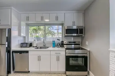 a kitchen with white cabinets and stainless steel appliances at Sunshine Manors 2017-3 in Fort Lauderdale