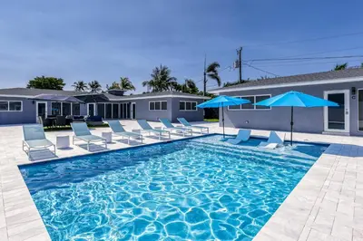 a swimming pool with chairs and blue umbrellas at Sunshine Manors 2013 B in Fort Lauderdale