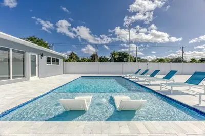 a swimming pool with lounge chairs and a house at Sunshine Manors 2013 B in Fort Lauderdale