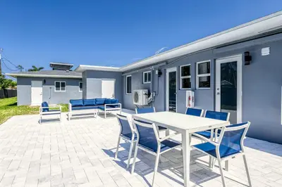 a patio with a white table and blue chairs at Sunshine Complex in Fort Lauderdale