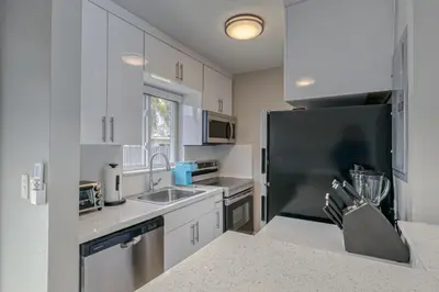 a kitchen with white cabinets and a black refrigerator at Sunshine Complex in Fort Lauderdale
