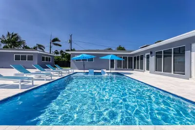 a swimming pool with blue chairs and a house at Sunshine Complex in Fort Lauderdale