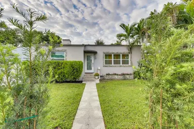 a white house with palm trees in the yard at Stylish Miami Home 2 Mi to Intracoastal Waterway! in Miami