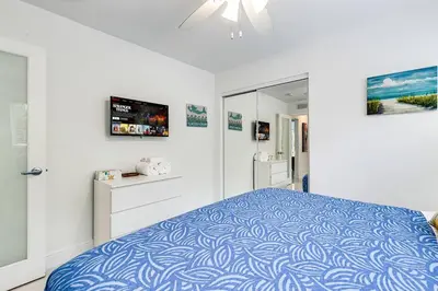 a white bedroom with a bed with a blue bedspread at 5BD House - Pool+BBQ+King beds - 3 min to beach in Hollywood