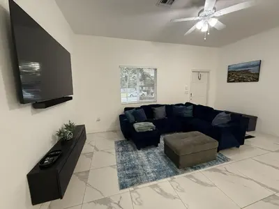 a living room with a blue couch and a flat screen tv at Mango Haus Near Beach, Cruise Port & Stadium in Fort Lauderdale