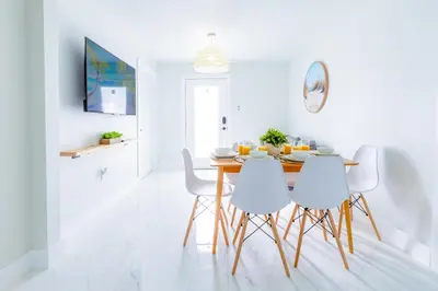 a dining room with a table and white chairs at Serenity Lodge Condo in Miami