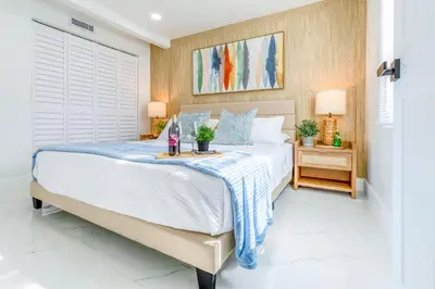 a bedroom with a white bed with a blue blanket on it at Serenity Lodge Condo in Miami