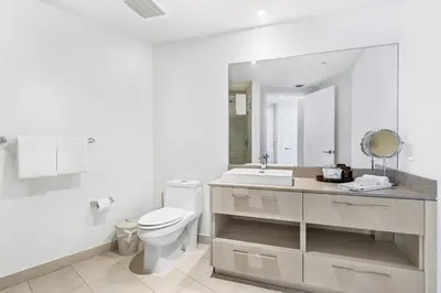 a white bathroom with a toilet and a sink at Ocean View Balcony with Pool Gym Access in Hallandale Beach